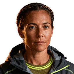 AI-generated portrait of a middle-aged woman with pulled-back hair and defined features, wearing a heavy work jacket, posed with a serious expression against a transparent background with hard lighting.