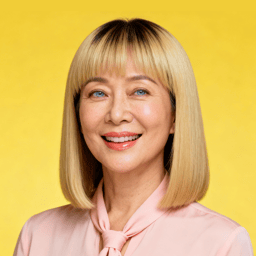 AI-generated portrait of a middle-aged woman with straight blonde hair and bangs, wearing a light blouse, posed with a warm smile against a transparent background in even lighting.