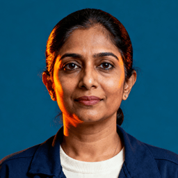 AI-generated portrait of a middle-aged woman with dark hair pulled back, wearing a simple blazer and top, posed with a calm expression against a muted blue background in soft lighting.