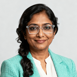 AI-generated portrait of a middle-aged woman with long dark hair and glasses, wearing a textured teal jacket and white blouse, posed with a warm expression against a light neutral background in soft lighting.