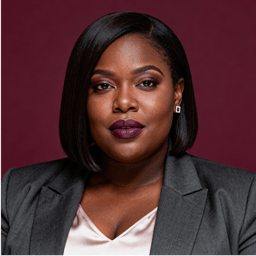 AI-generated portrait of a middle-aged woman with a sleek bob haircut, wearing a tailored blazer and blouse, posed with a serious expression against a deep burgundy background in controlled studio lighting.