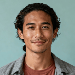 AI-generated portrait of a young man with wavy hair pulled back and light facial hair, wearing a casual jacket over a t-shirt, posed with a gentle smile against a muted teal background in soft diffused light.