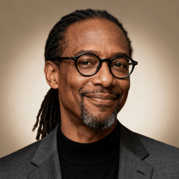 AI-generated portrait of a middle-aged man with long locs pulled back, round glasses, and a short goatee, wearing a blazer over a dark top, posed with a gentle smile against a warm neutral background in clean studio lighting.