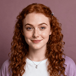 AI-generated portrait of a young woman with long curly red hair and freckles, wearing a light top and cardigan, posed with a subtle smile against a muted mauve background in warm studio light.