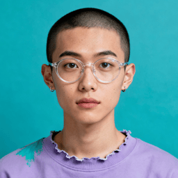 AI-generated portrait of a young person with a shaved head and clear-framed glasses, wearing a sweatshirt with paint marks, posed with a neutral expression against a teal background in soft studio light.