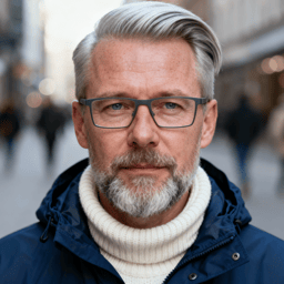 AI-generated portrait of a middle-aged man with short gray hair and a beard, wearing glasses and layered outerwear, posed with a calm expression against a city street background in soft daylight.