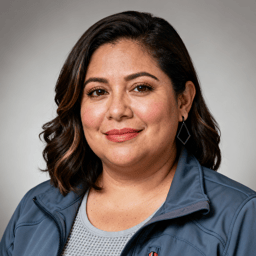 AI-generated portrait of a middle-aged woman with shoulder-length hair, wearing a gray technical jacket, posed with a relaxed expression against a light neutral background in soft directional lighting.