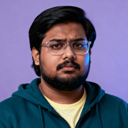 AI-generated portrait of a young man with medium-length hair, glasses, and light facial hair, wearing a hoodie over a T-shirt, posed with a serious expression against a purple indoor background in soft light.