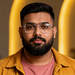 AI-generated portrait of a young man with short hair and glasses, wearing a casual jacket and T-shirt, posed with a neutral expression against a warm-toned background in crisp lighting.
