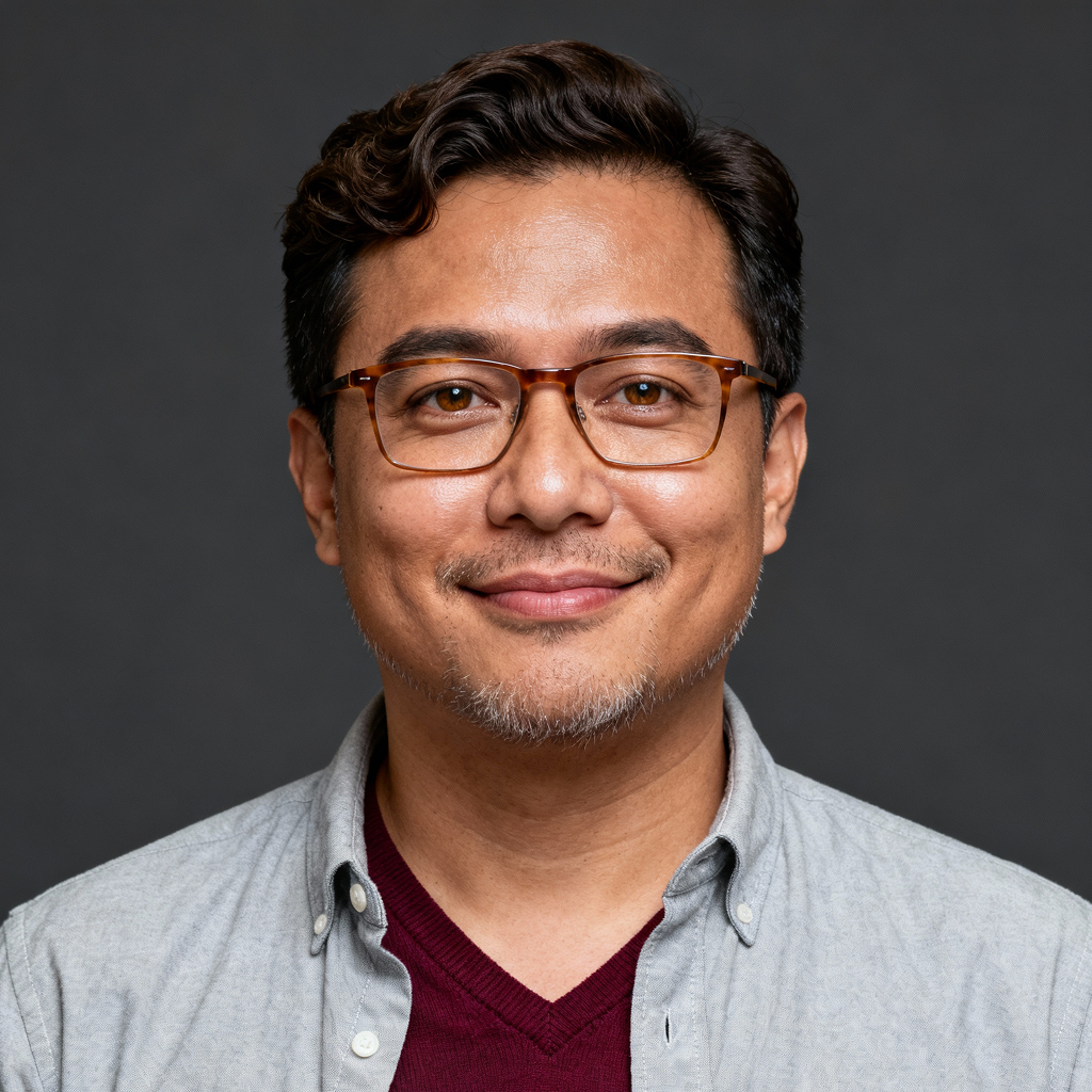 AI-generated portrait of a young man with short curly hair and glasses, wearing a button-up shirt and cardigan, posed with a soft smile against a dark gray background in diffused light.