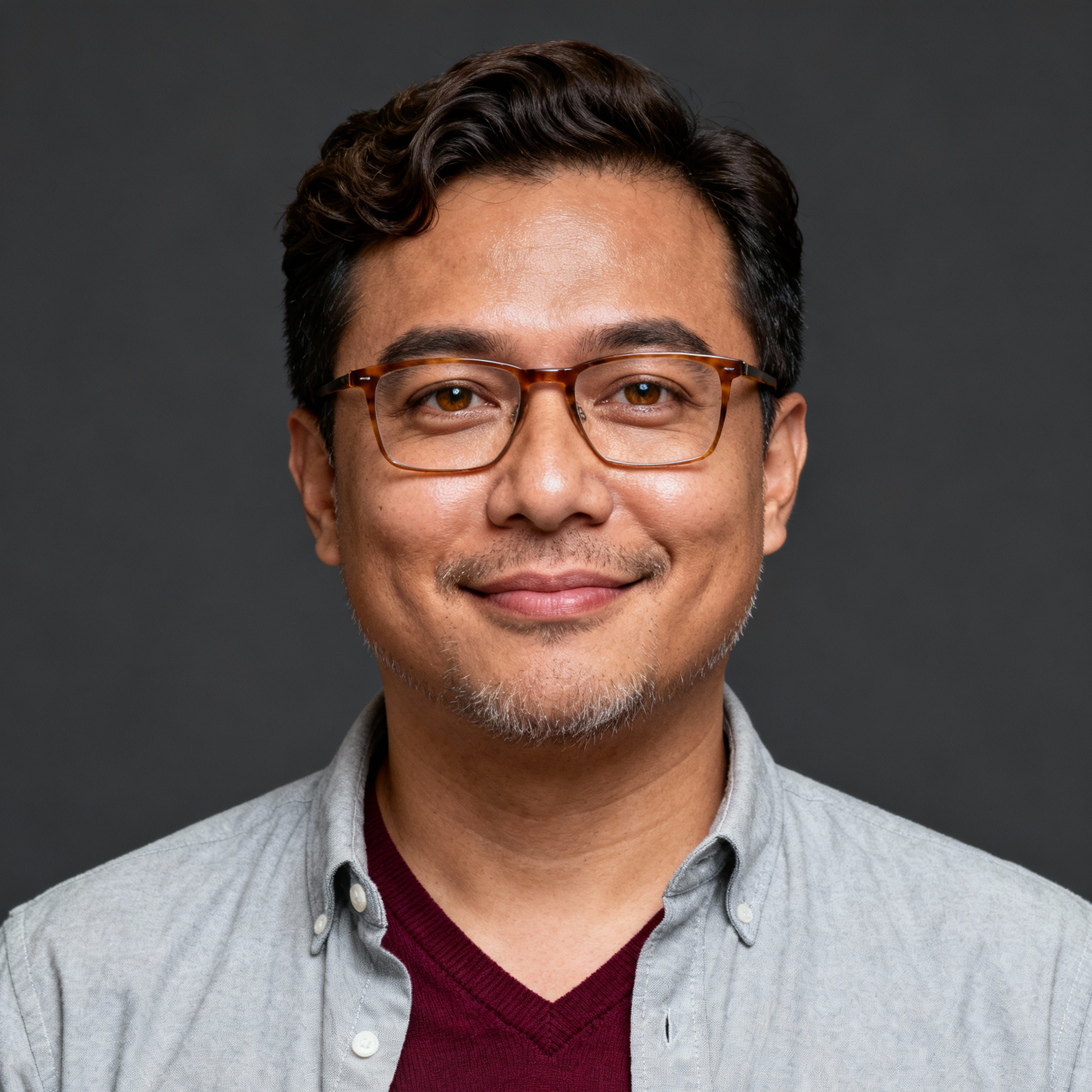 AI-generated portrait of a young man with short curly hair and glasses, wearing a button-up shirt and cardigan, posed with a soft smile against a dark gray background in diffused light.