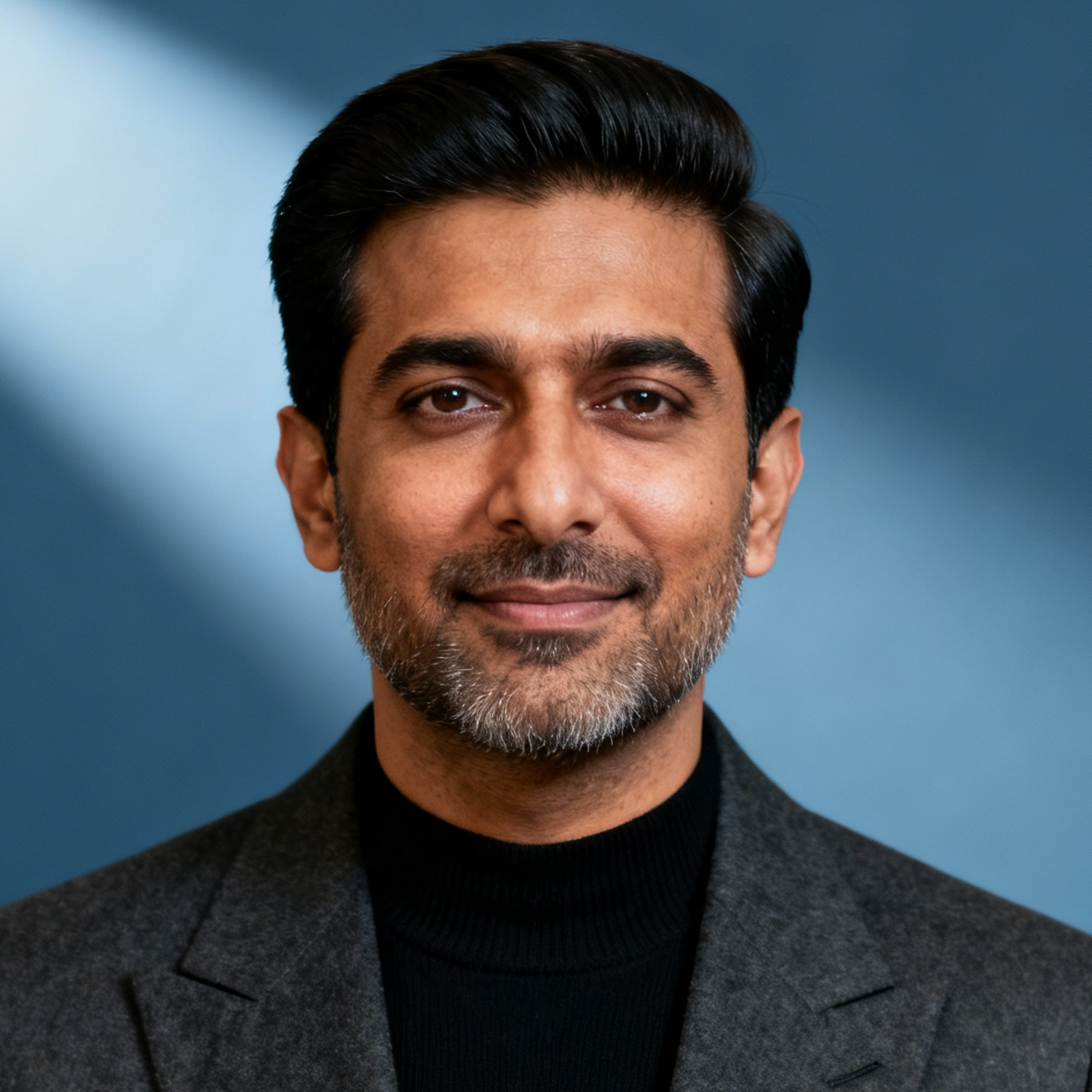 AI-generated portrait of a middle-aged man with neatly styled hair and light facial hair, wearing a blazer over a dark top, posed with a calm expression against a muted blue background in studio lighting.