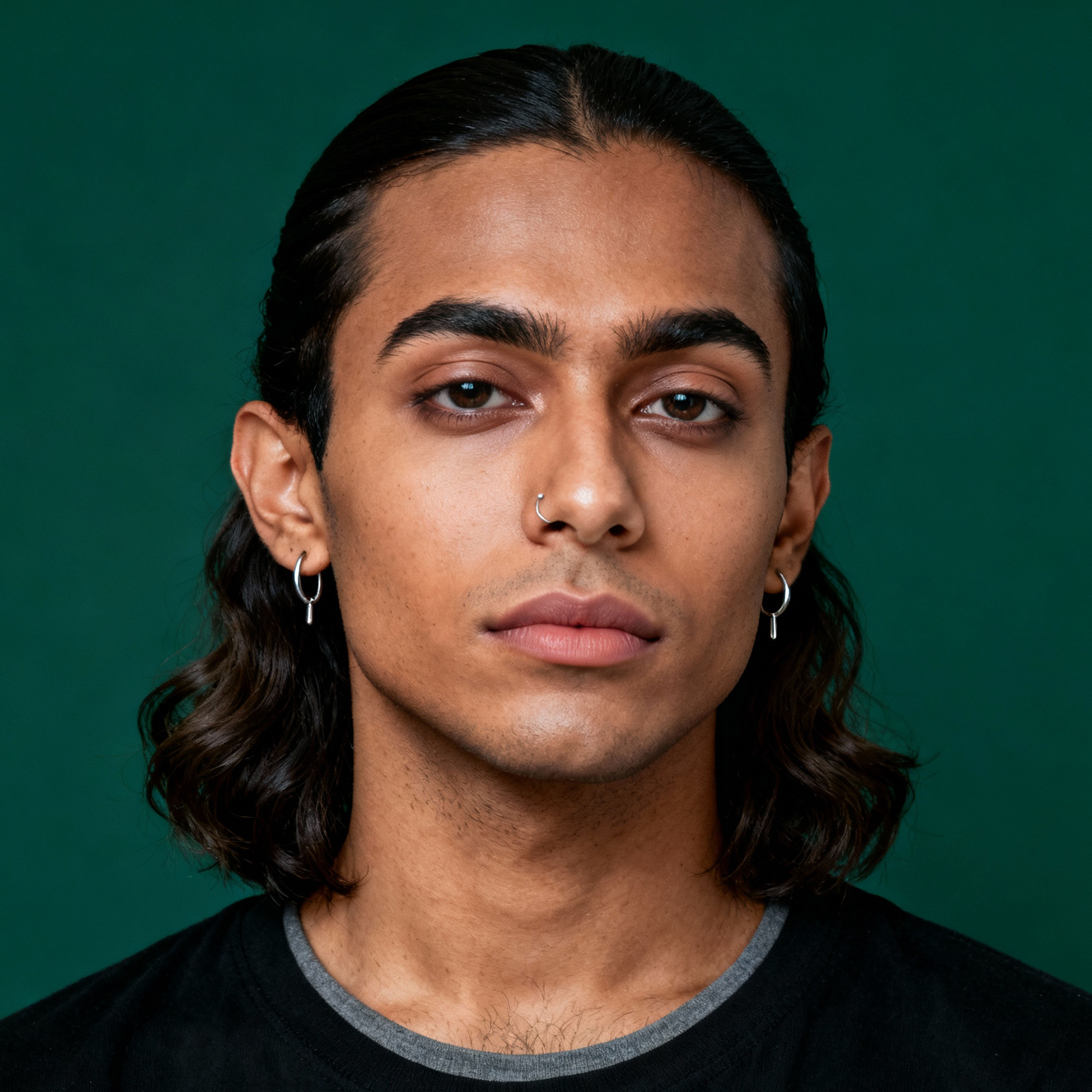 AI-generated portrait of a young person with shoulder-length dark hair and earrings, wearing a dark t-shirt, posed with a neutral expression against a deep green background in balanced light.