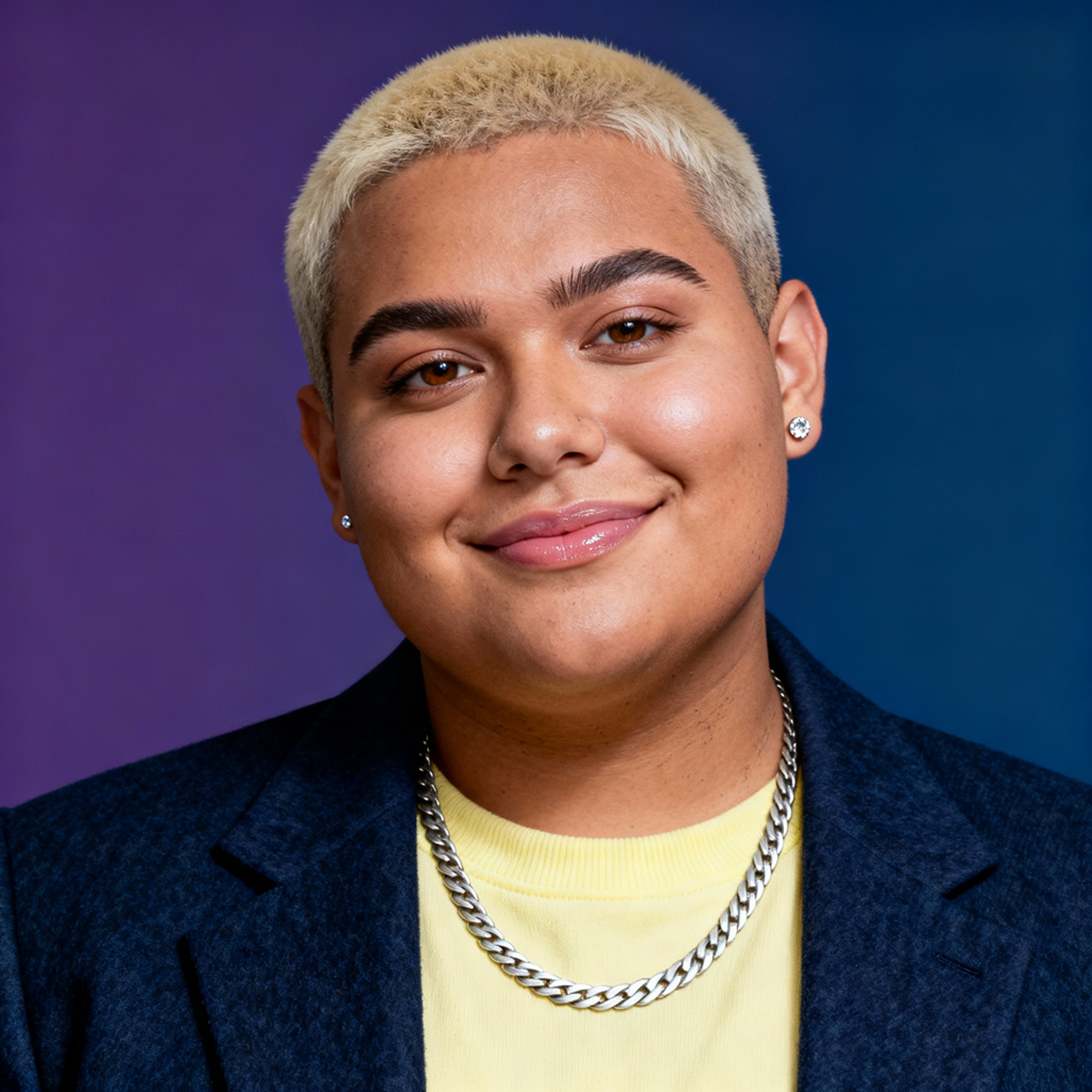 AI-generated portrait of a young person with very short hair, wearing a blazer over a T-shirt with a chain necklace, posed with a gentle smile against a blue-to-purple gradient studio background in soft light.